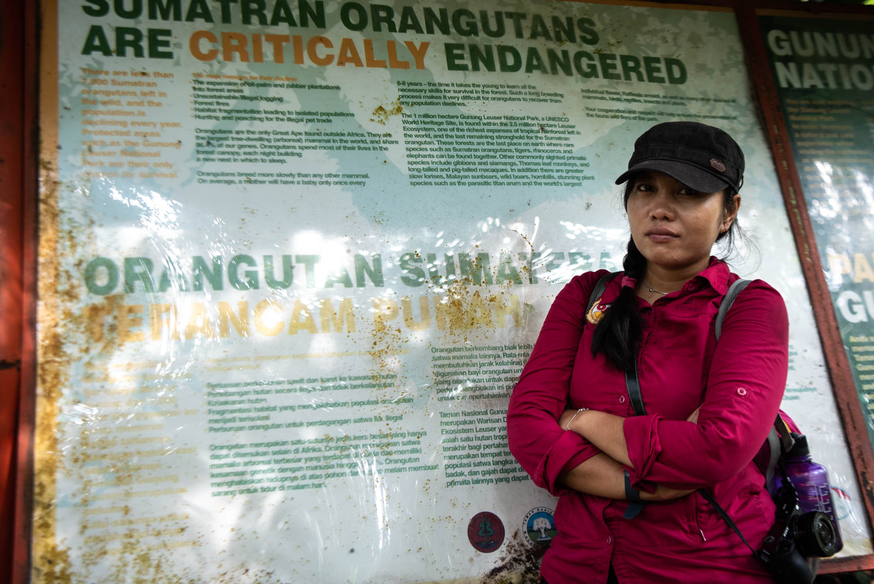 Orangutan Information Centre communications coordinator stands next to an information board