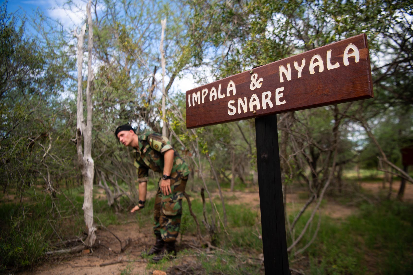 A sign reads "Impala & Nayla snare" with a Protrack Anti-Poaching Unit instructor pointing behind it