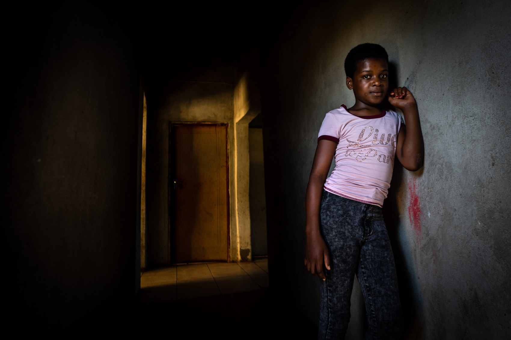 An African girl leaning on a wall inside a house in South Africa